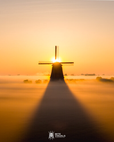 Aerial drone view of a classic Dutch windmill during sunrise with fog, Schermerhoorn, spring in Holland, The Netherlands